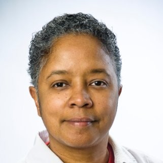 Eva has short hair. She is wearing a white collar shirt in front of a light background