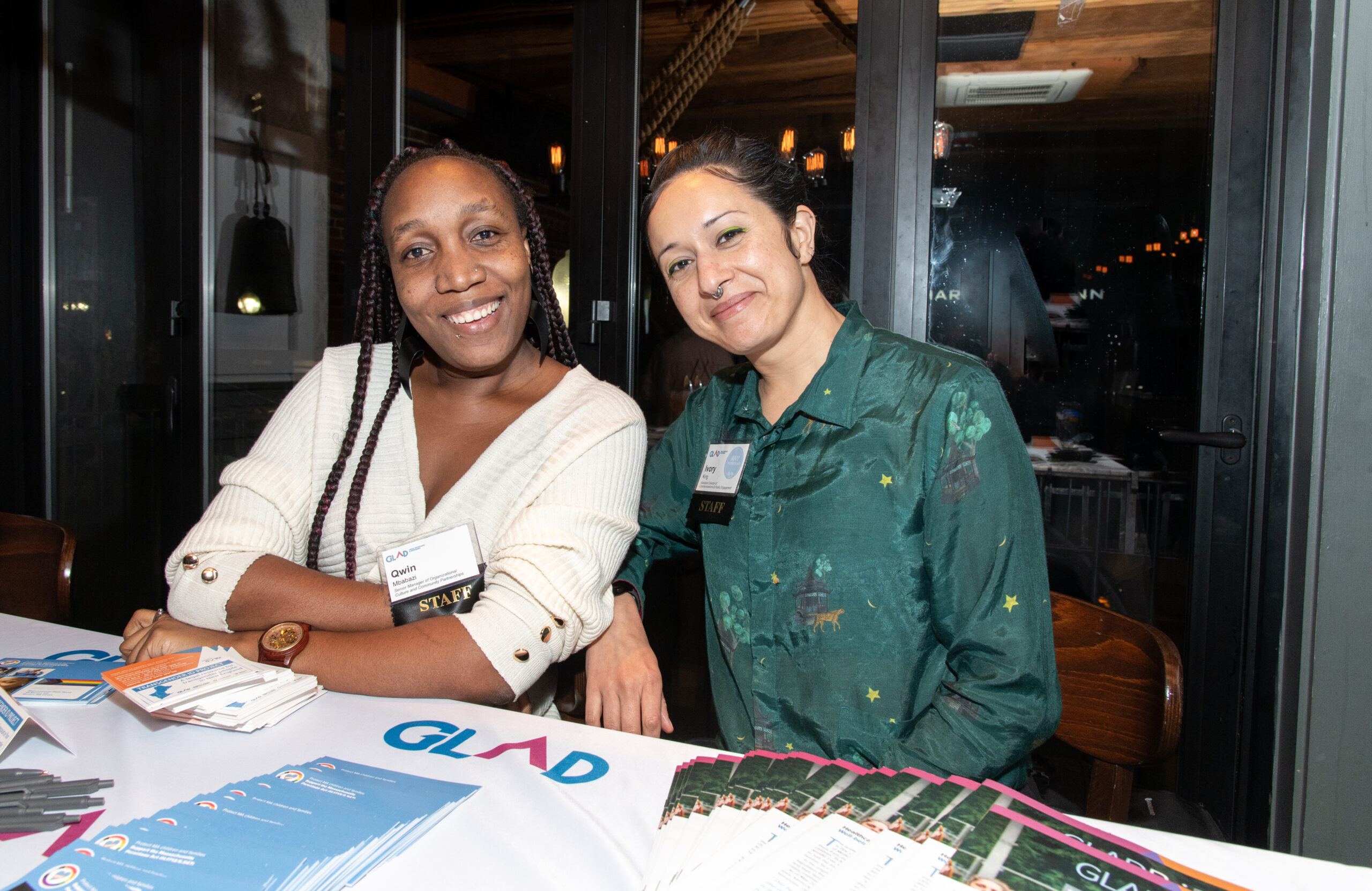 Two GLAD Law staff members smiling behind a table of informational materials at an event