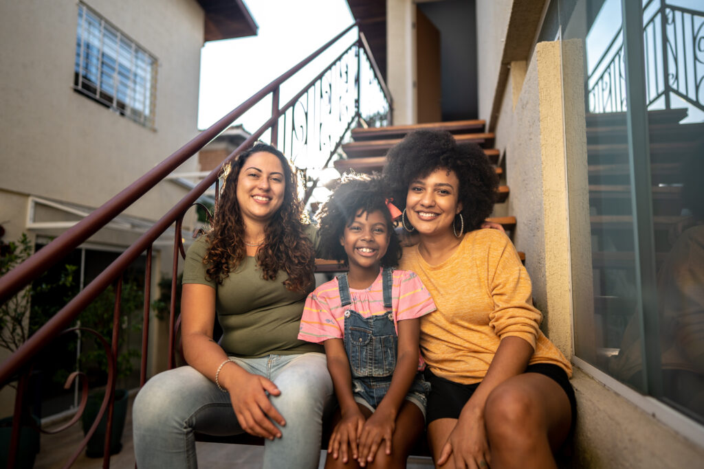 Two moms smiling with their young daughter