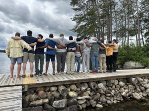 The fathers from The Dads documentary standing arm in arm on a dock looking over water
