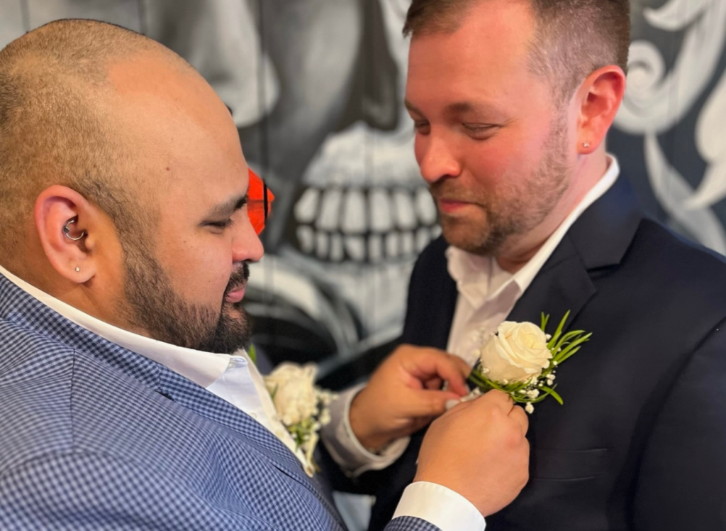 GLAD Law staff Chris Borger-Hernandez pins a boutonniere on his husband before their wedding.